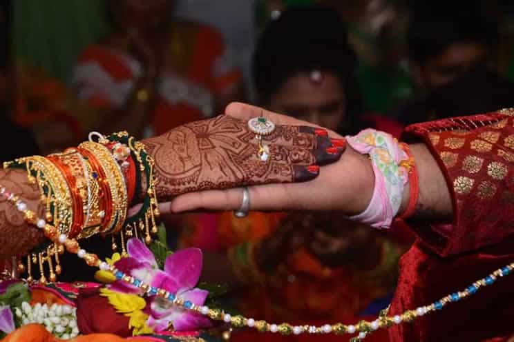 hindu brides hand placed on top of hindu grooms hand