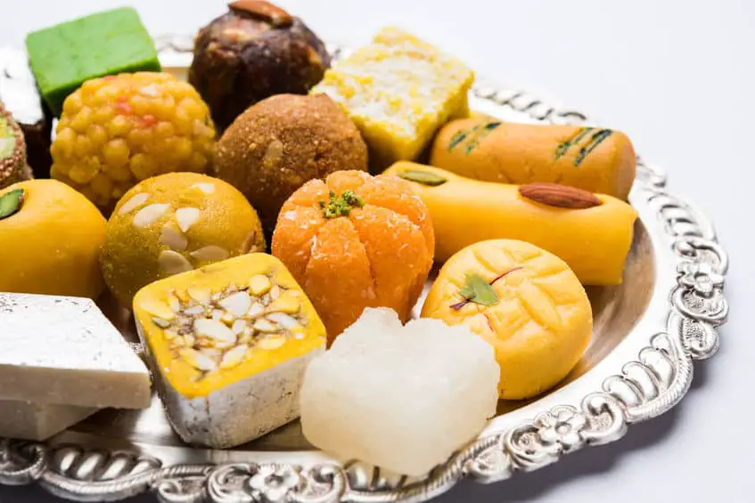 Indian sweets served in silver plate. variety of Peda, burfi, laddu in decorative plate