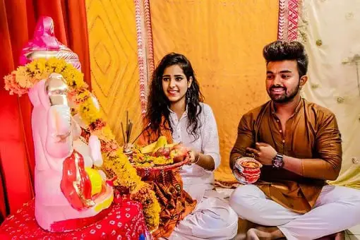 Couple sitting in front of Ganesh idol doing puja