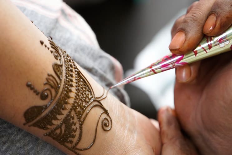 Woman applying mehndi to bride