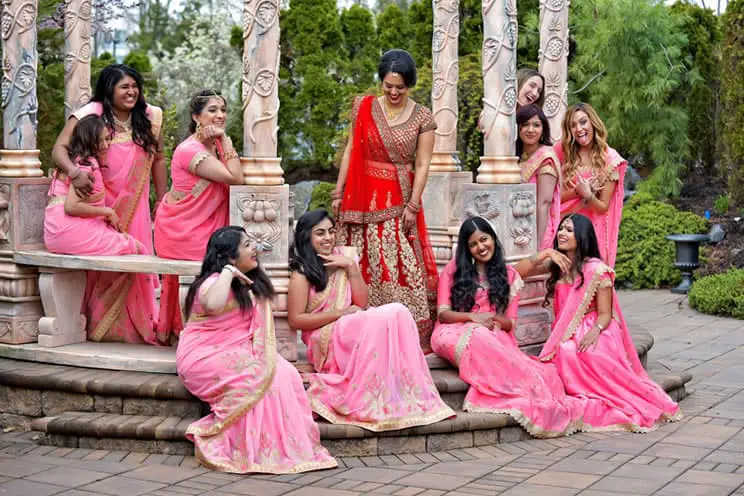 Hindu bridesmaids sat outside dressed in ink saris