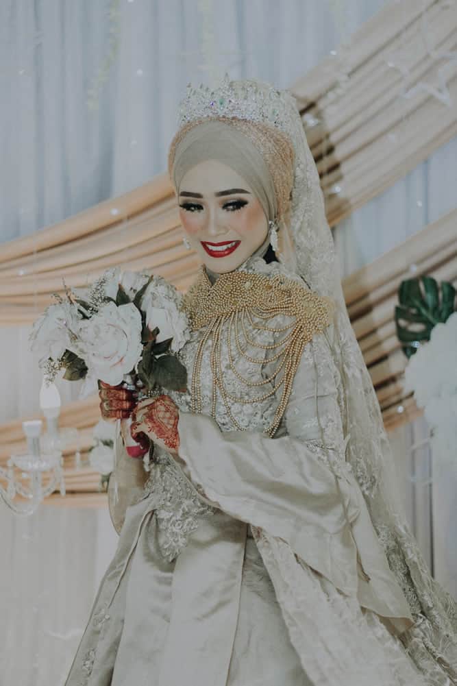 Muslim woman wearing wedding dress and holding flowers