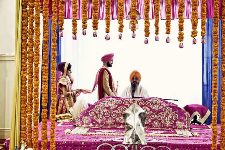 Sikh bride following Sikh groom around the Sikh holy book in Sikh temple