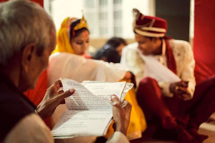 Mantras Ritual during Hindu Marriage at Mandap in presence of Bride Groom. Camera focus is on mantra book in the hand of the priest