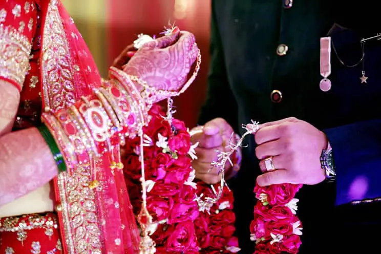 Hindu bride and groom standing opposite each other at Indian wedding and making their pheras